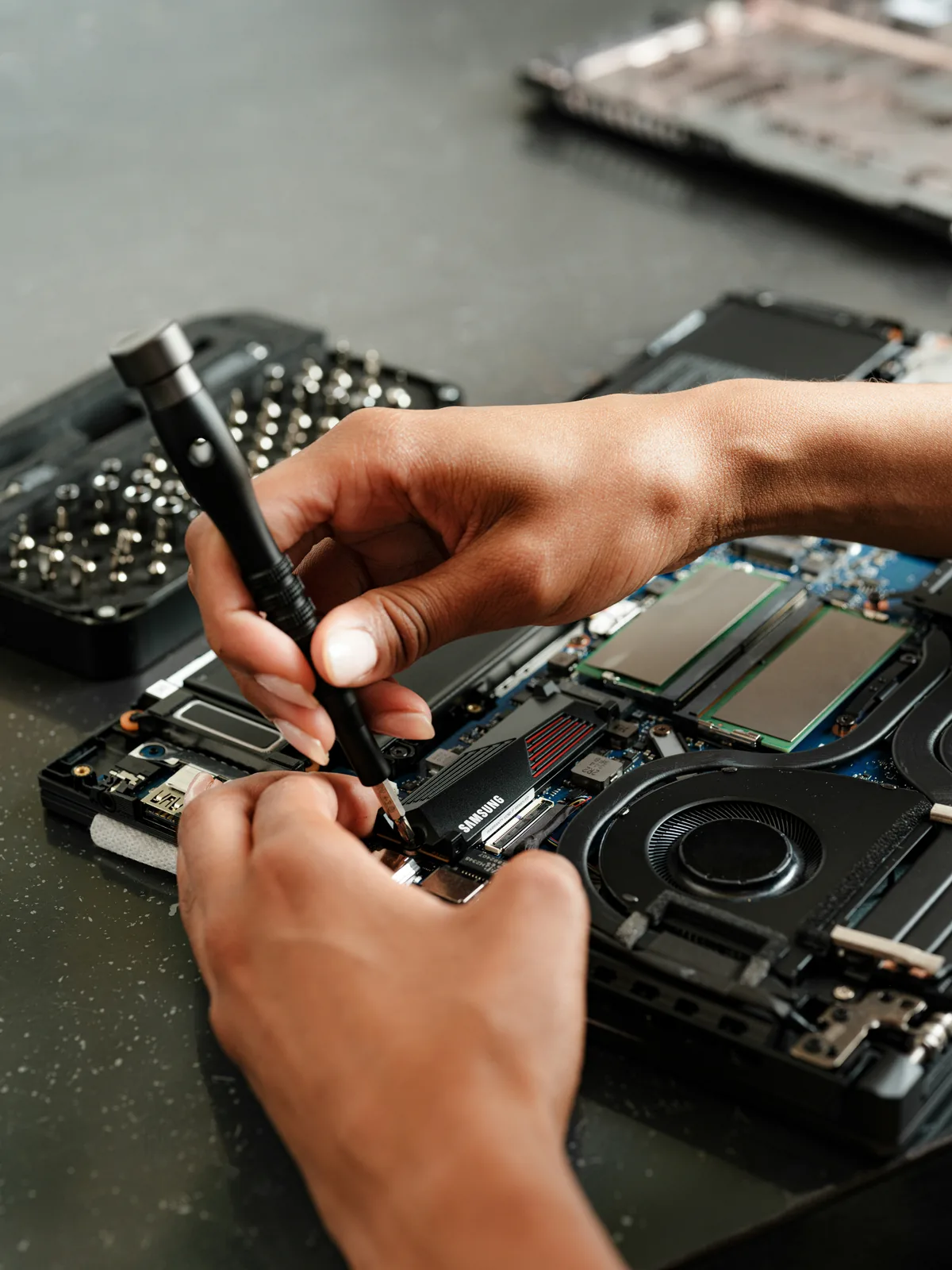 Technician installing an SSD in an open laptop